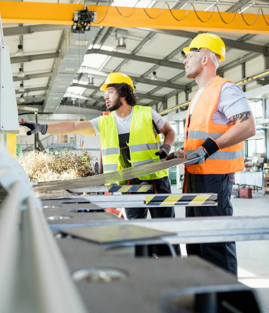 Male manual workers manufacturing sheet metal at industry